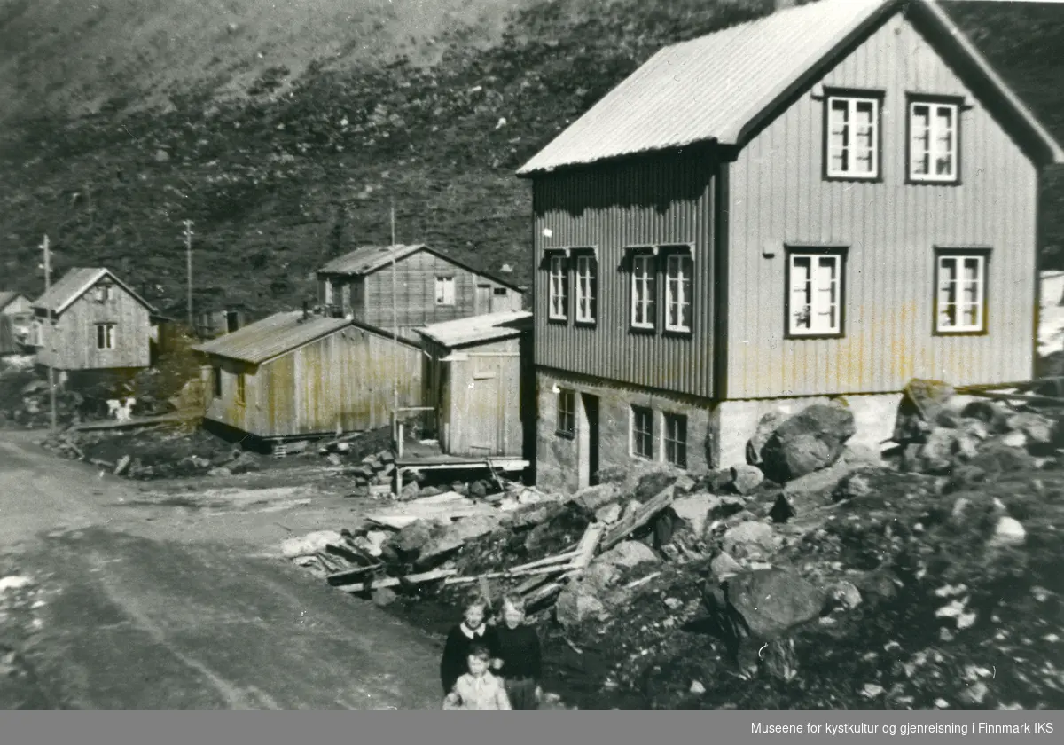 Kuvika i Kamøyvær. Gjenreisningsbebyggelse med brakker og et ferdig bygget hus. Nederst i midten ser man tre barn. 1950-tallet.