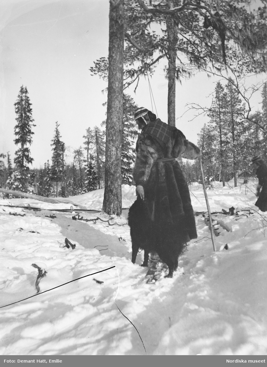 Kvinna, Emilie Demant Hatt, leker med hunden Rill i snön. Troligen under höstflyttningen vid Laimo. Bilden ingår i en serie fotografier tagna av Emilie Demant Hatt i Sapmi mellan åren 1907 och 1916.