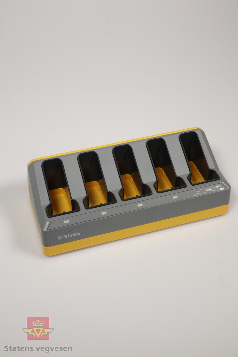 En gul og grå batterilader fra Trimble med plass til fem batterier.