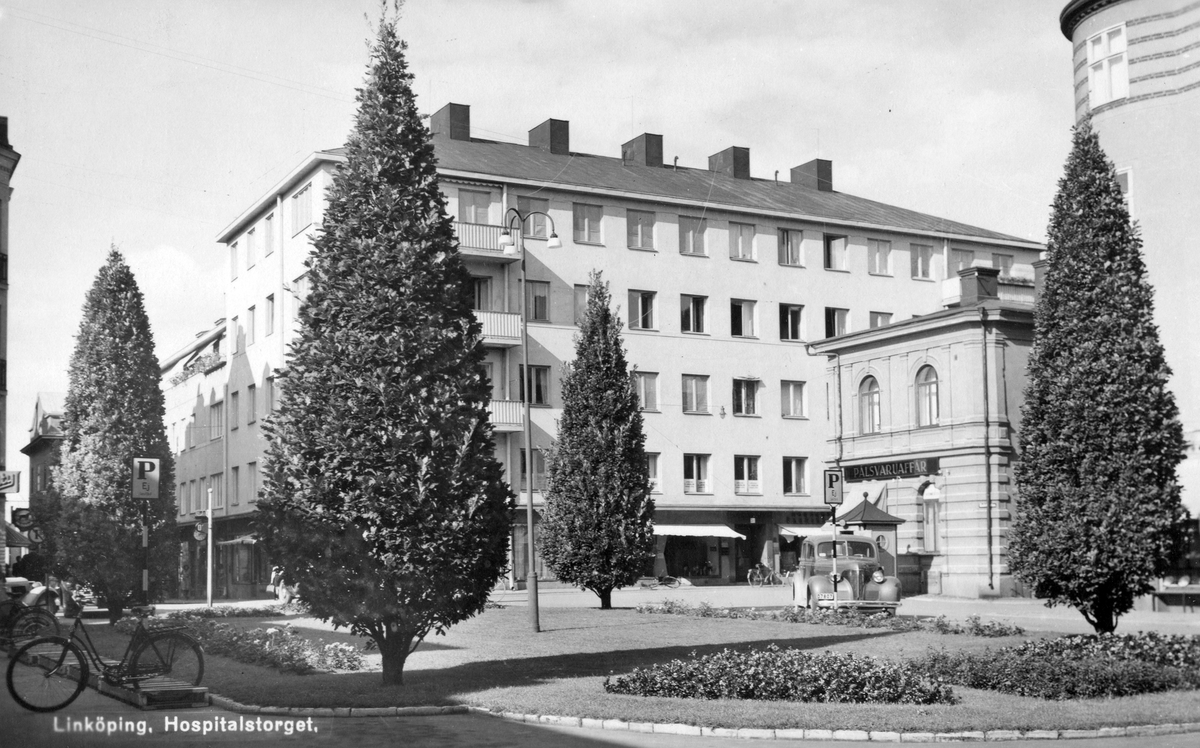 Ett år 1951 postgånget vykort med motiv från Hospitalstorget i Linköping. Vy mot nordost med bebyggelse inom kvarteret Domaren i fonden. Den låga, rustika byggnaden till höger i bilden uppfördes 1884 efter ritningar av Sven Hansson Gratz. Fastigheten inrymde en längre tid körsnärsfirman Aeimertohn.
