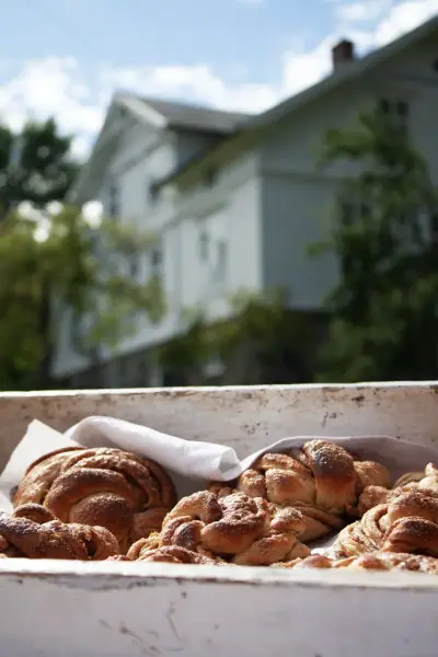 Kanelknuter i forgrunnen med hvitmalt hus i bakgrunnen.