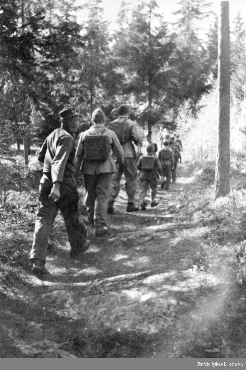 AT-leir  (arbeidstjeneste) 2. verdenskrig ca.1943. Leiren lå der Varteig skole ligger i dag. 
Gruppe marsjerer på vei til arbeidsfeltet, ant. ved Brunsbybekken..