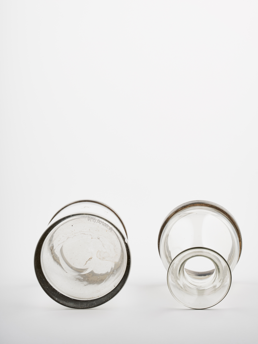 Karaffel i glass som kan deles i to på midten ved å skru delene fra hverandre. Skrupartiet er i metall.
