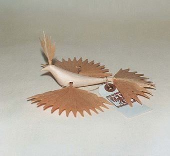 Spånfågel med vingar, kam och stjärtfjädrar av spån från furu fastsatta på en kropp av lövträ. Har krok för upphängning i ryggen.
