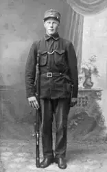 Portrett av soldaten Jørgen Jakobsen med gevær ved siden av 