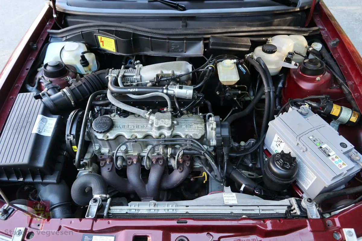 Opel Astra 2.0 I GLS. Rød 4 dørs personbil med 4 hjul og framhjulstrekk. Bilen har en bensindrevet 4-sylindret rekkemotor (forbrenningsmotor) med et sylindervolum på 1998 kubikkcentimeter og en effekt på 85 kW (116 hk). Motorbetegnelsen er C20NE. Girkassen er en 5-trinns manuell type. Bilen fremstår som original og nesten ubrukt med ca. 6000 km på telleren. Den har noen små sår i lakken og har aldri vært omlakkert. Lakk/trimkode er E-549 - 151. Dekk foran og bak skal være 175/65 R 14. Fem sitteplasser.
