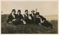 En gruppe mennesker sitter ute på gresset, en av kvinnene ha
