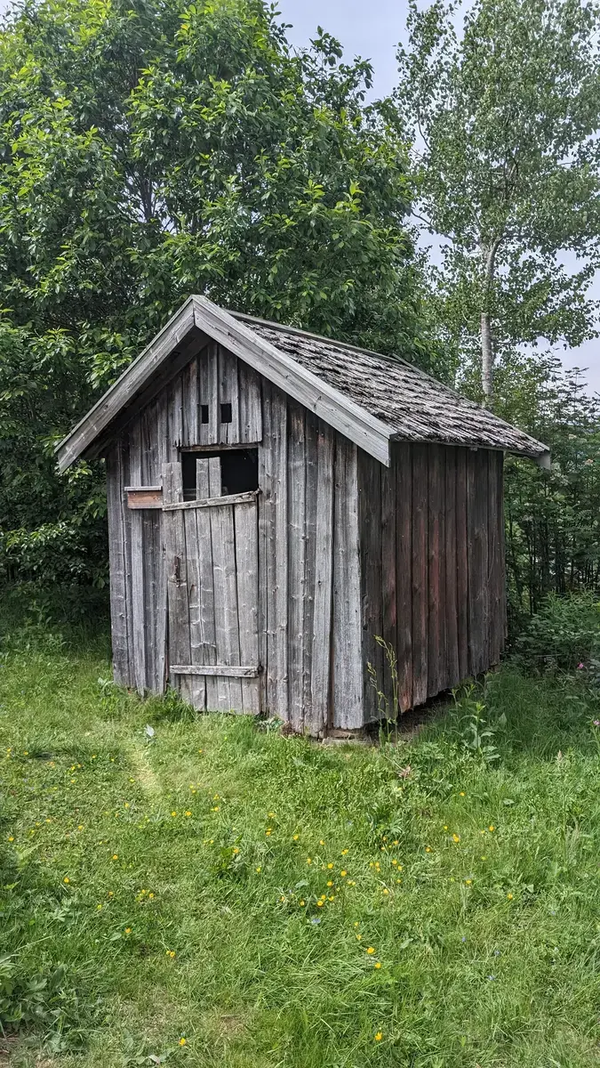 Bilde av en gammel utedo laget av treverk.