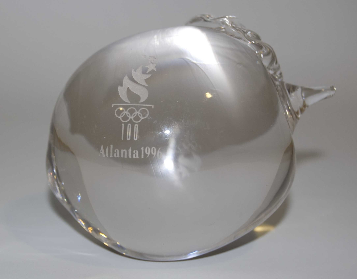 Pyntegjenstand av glass formet som et eple. På gjenstanden er det emblem for de olympiske sommerleker i Atlanta i 1996.
