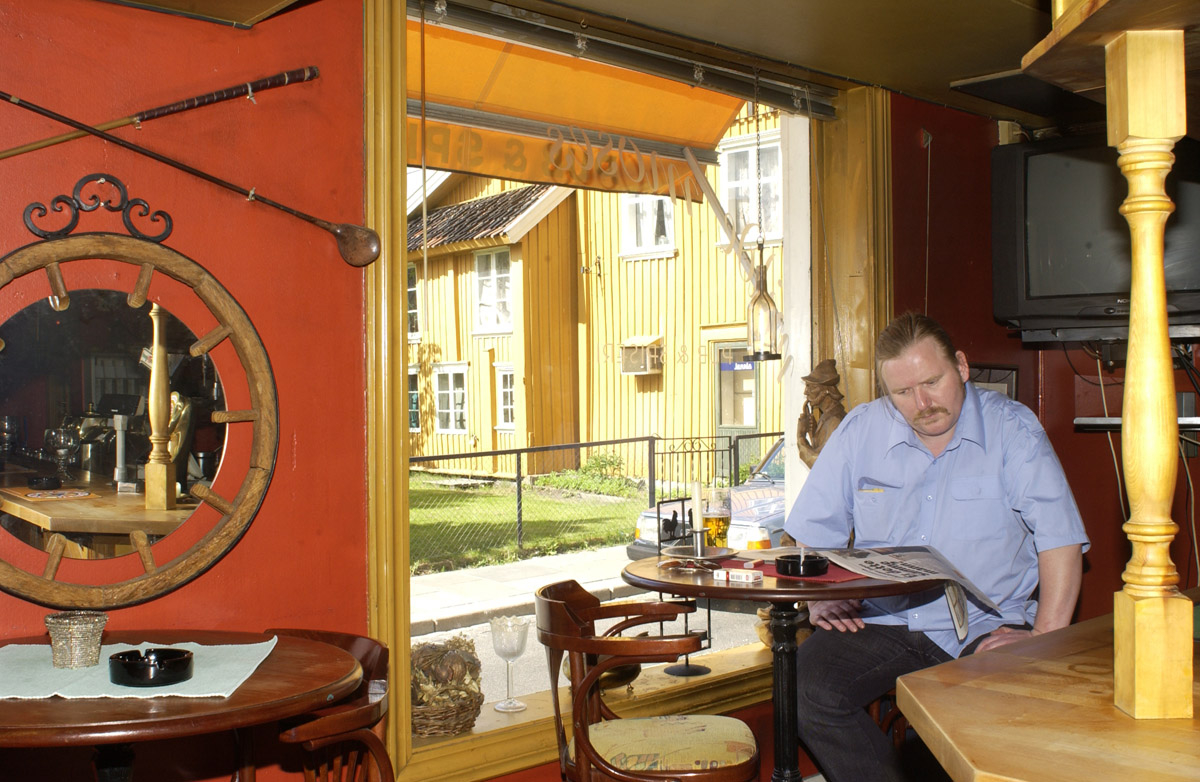 Pubgjest med røyk, øl og avis ved vinduet Milde Moses Pub & Spiseri i Drøbak