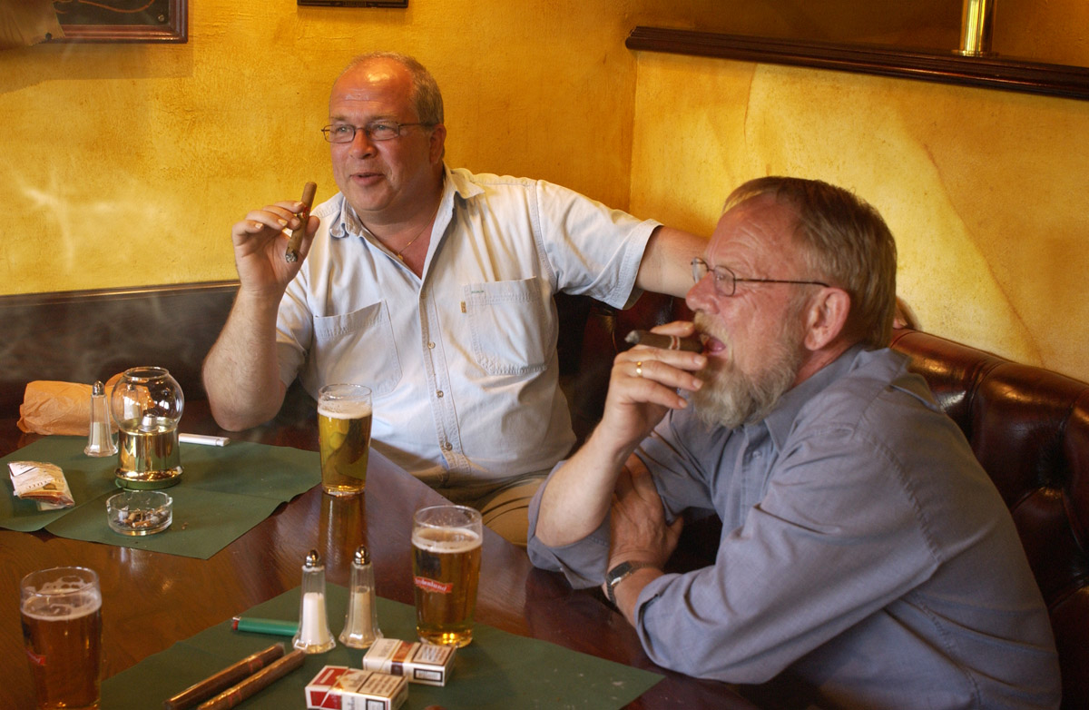 2 menn ved et bord med sigarer. Bowler & Spisepub.