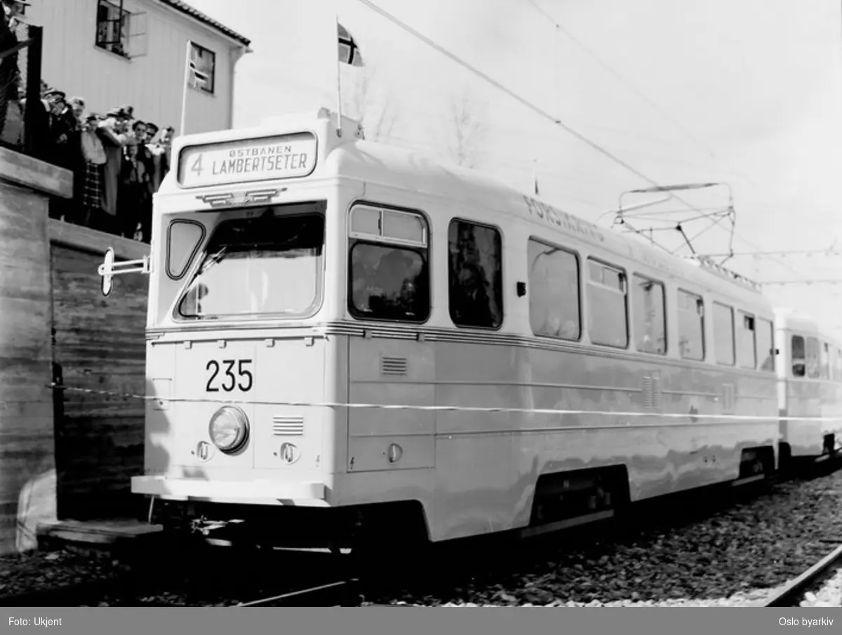 Oslo Sporveier. Trikk motorvogn 235 type Høka MBO med tilhenger på linje 4, Lambertseterbanen, vogna sprenger snora ved Høyenhall stoppested og markerer dermed at banen er åpnet 28. april 1957. Tilskuere.