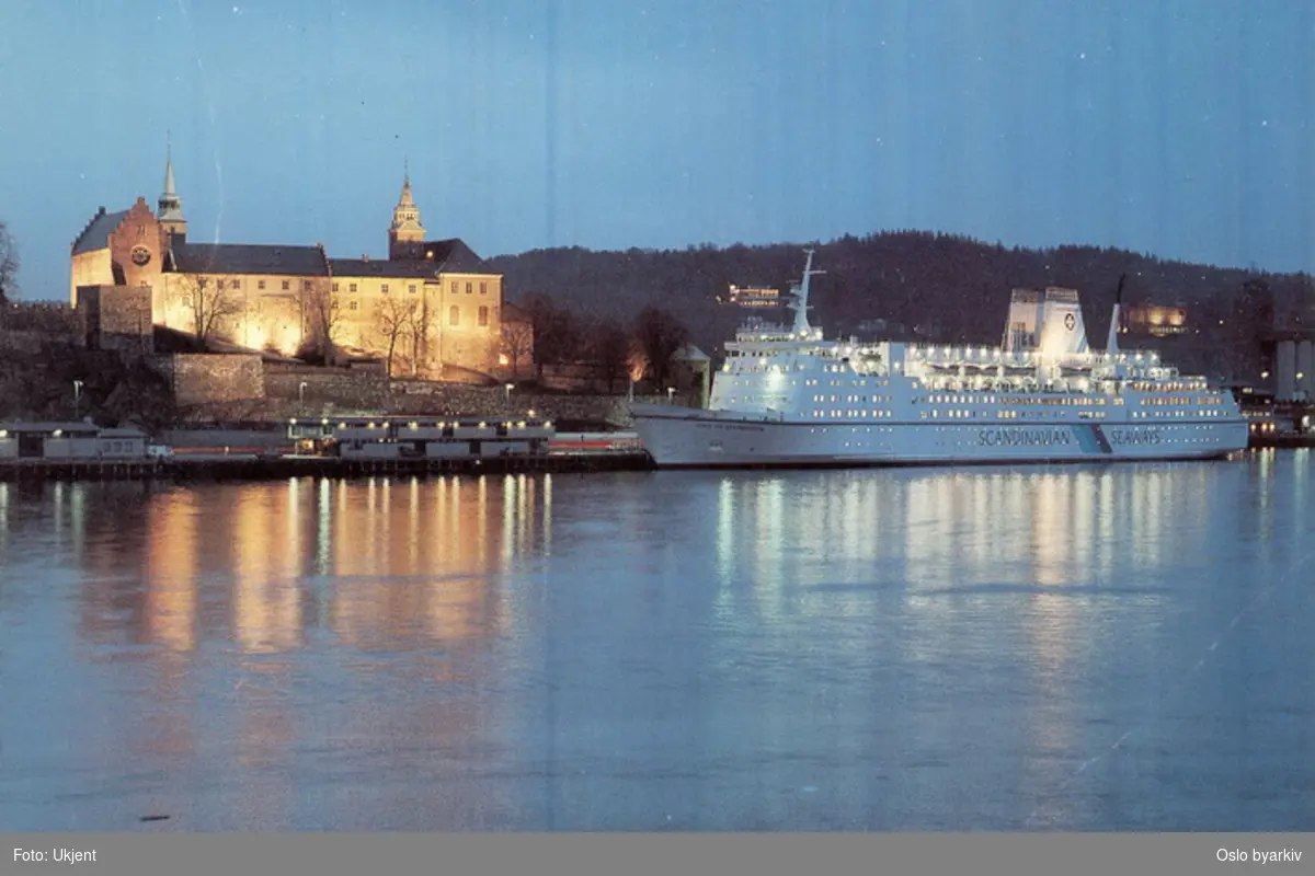 Danskebåten MS King of Scandinavia ved havn langs Akershusstranda under et flombelyst Akershus slott. Postkort.