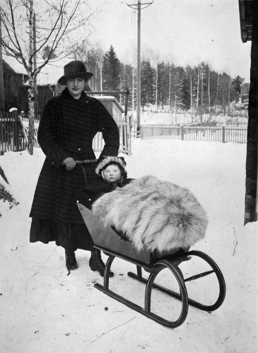 Ringsaker Moelv, Marie Johanne Dobloug (1916-2000) kallenavnet "Tubbi" ble gift Tørud, kjører sitt barn i en sluffe, datter av M. P. Dobloug og tannlege Clara født Gjestvang,
