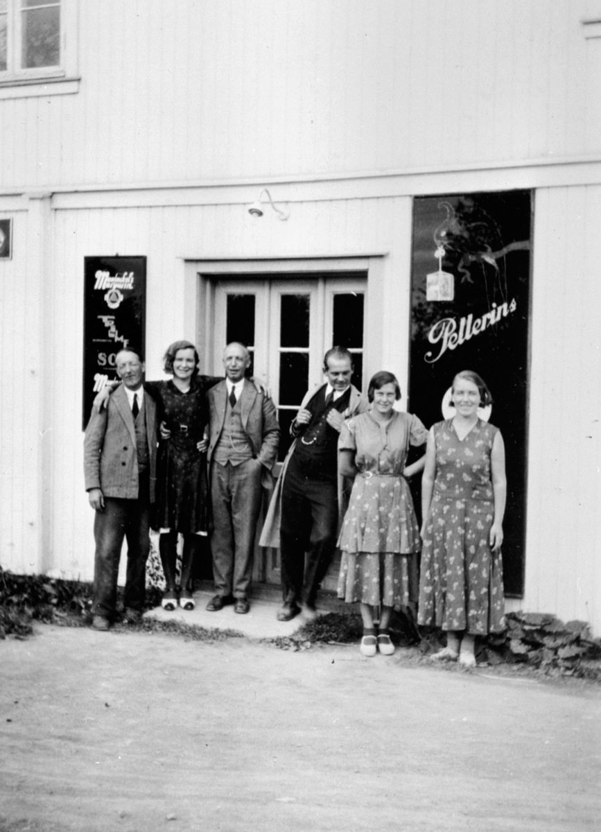 Personalet foran butikken til Grønnerud i Dalby på Helgøya. Reklameskilt. Landhandleri.