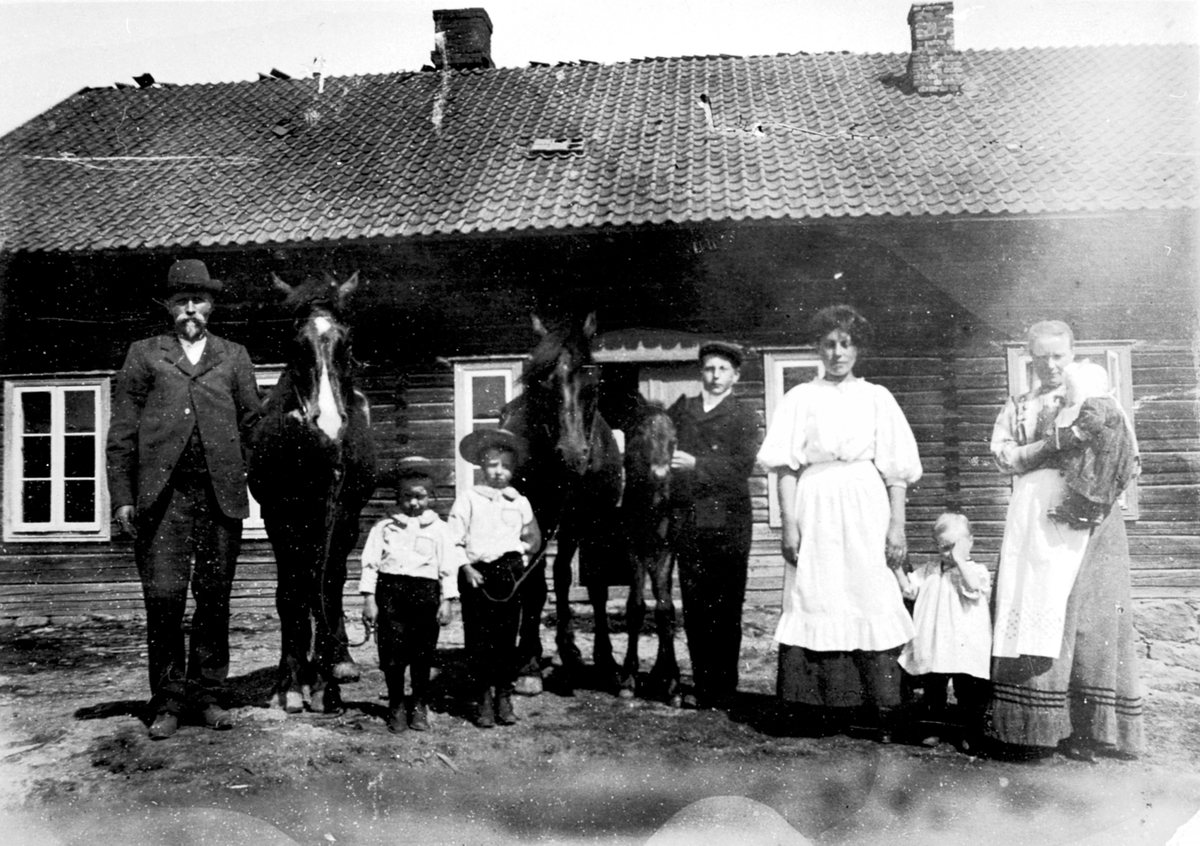 Utendørs på Syverud gård, Solbergåsen, Nes, Hedmark. Fra venstre er Lars H. Fossum f.1875, Leonard Fossum f. 1906, Hans Østby f.1905, ukjent, Maren "pige", Karen Fossum f.1909, Gund Fossum f.1874 med Dorthea F.1911 på armen.