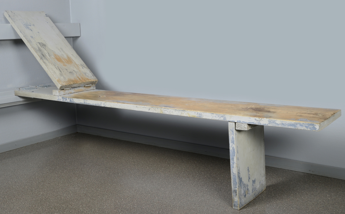Sammensatt benk med rygglene. Benken er laget av tre deler, benk, rygglene og fot, og kan slås sammen og opp mot veggen.