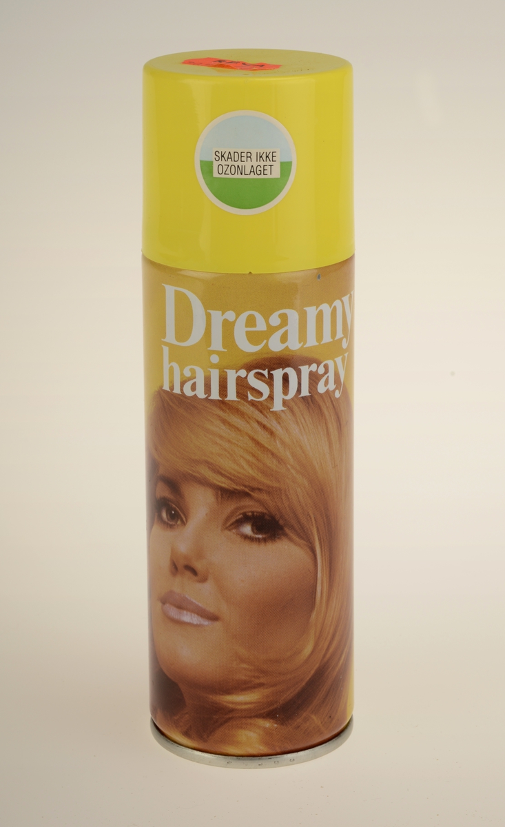 Sylinderformet aerosolflaske for hårspray. Gul plasthette, metallbeholder med påtrykket motiv.