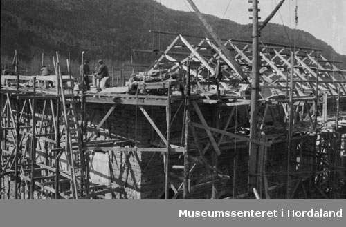 Reising av tak på Herlandsfossen Kraftverk, taksperrer og stillas i trevirke, arbeidare i sving, kran til løft av material