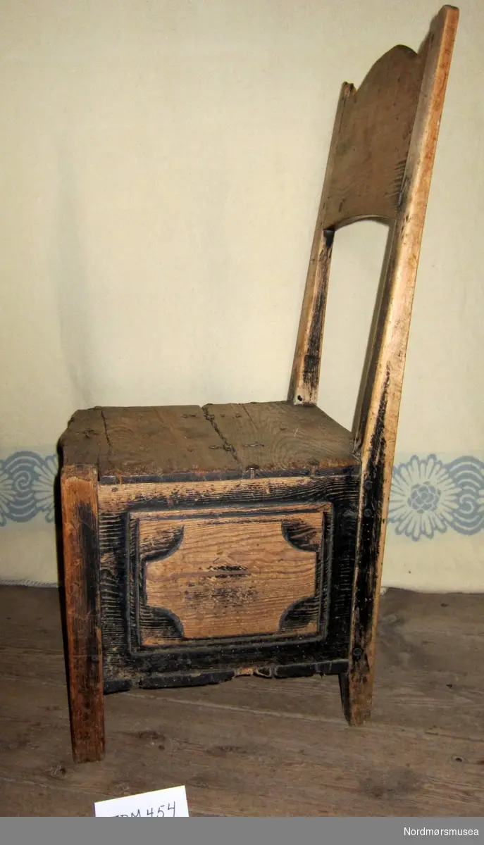 Stol med lokk i setet, brukt til oppbevaring av handarbeid. Sjølve kista har utheva firkantar i fronten og sidene. Enkel lås til kistlokket.