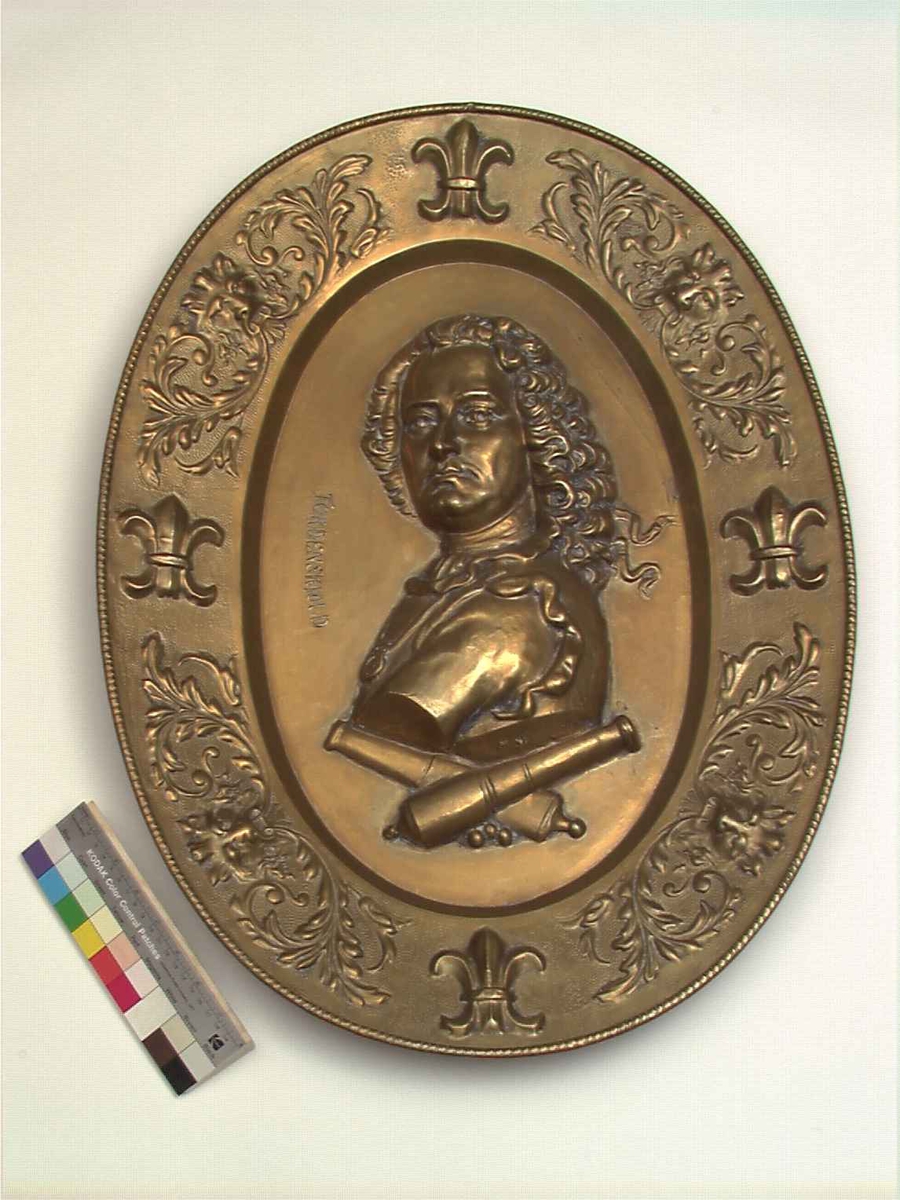 Messing. Ovalt, i bunnen Tordenskjolds brystbilde i relieff, derunder 2 korslagte lavetter, border og franske liljer, akantus og løvemasker.
