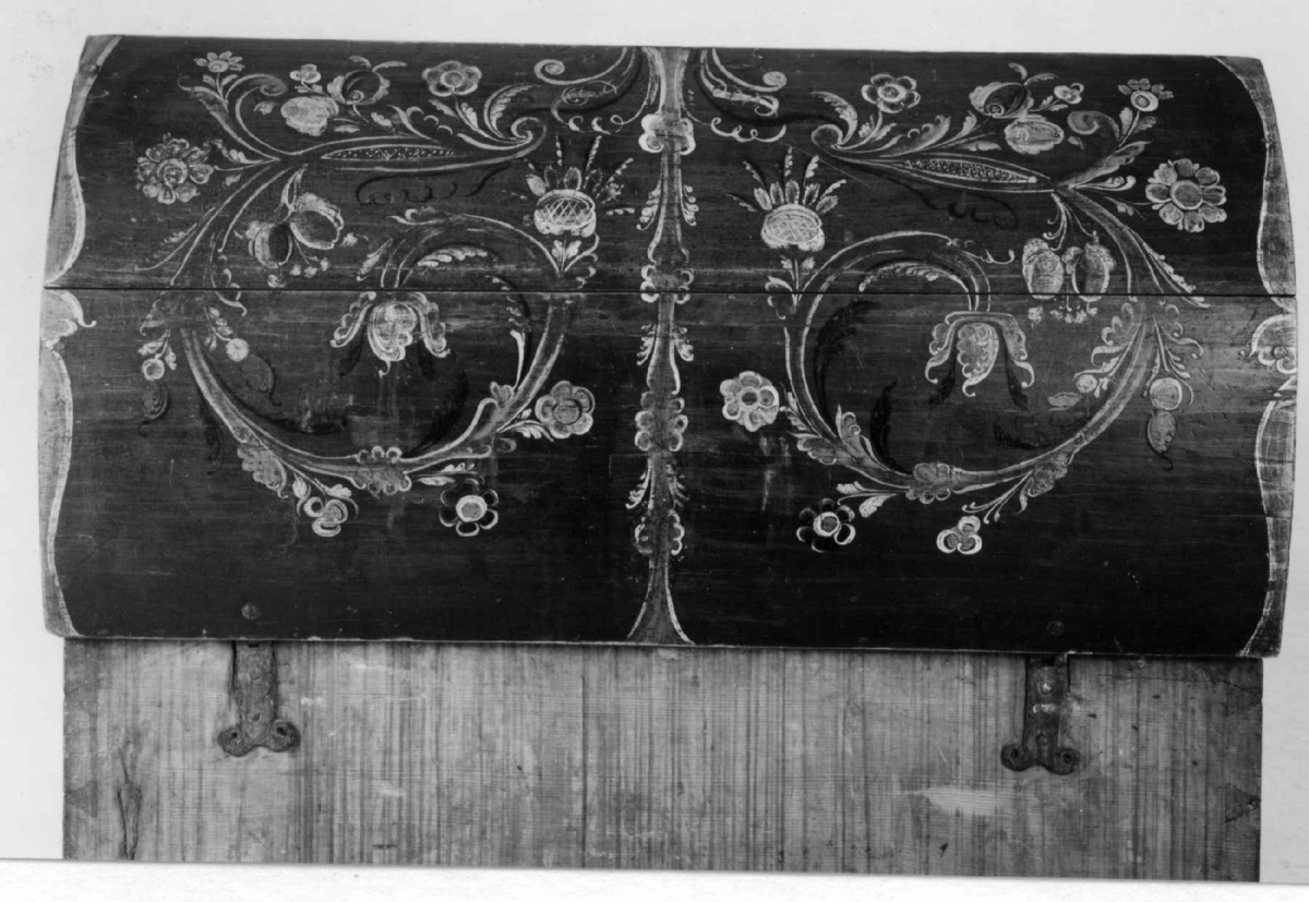Kiste med buet lokk og rosemalt. På forsiden tre arkader, kortside ådret.