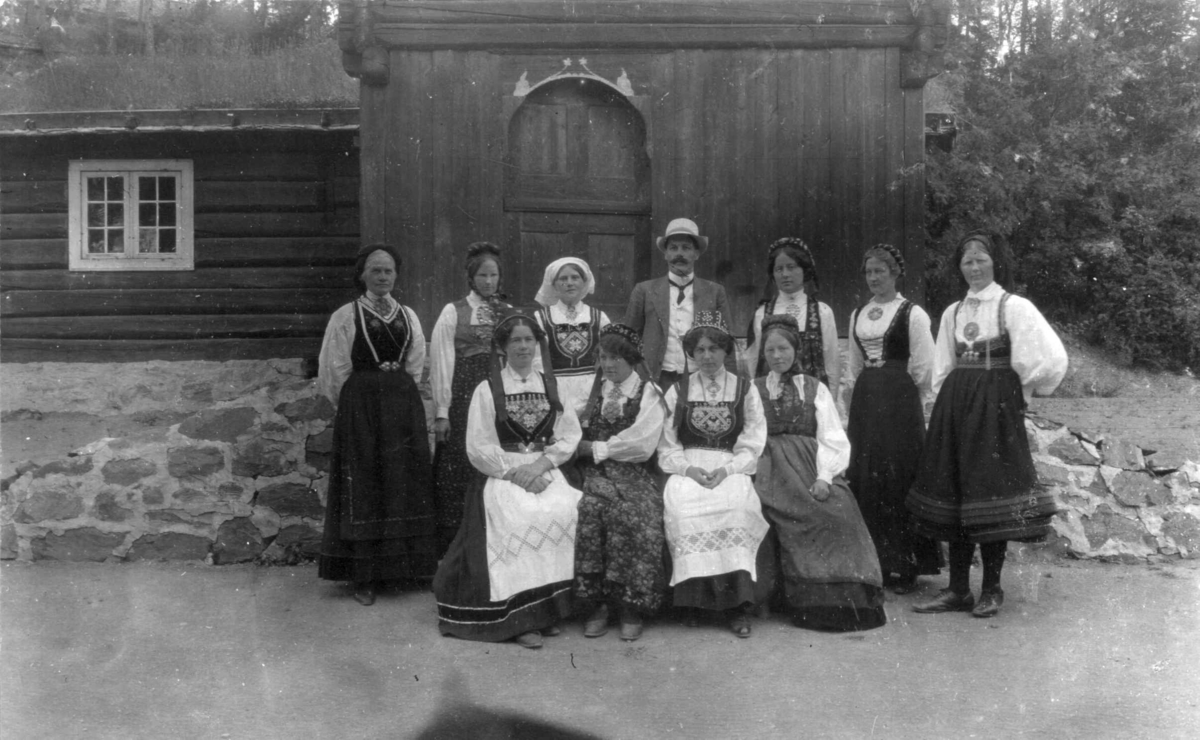 Inspektør Sørum omkranset av oppsynsdamer i drakter på Norsk Folkemuseum, fotografert før 1916.