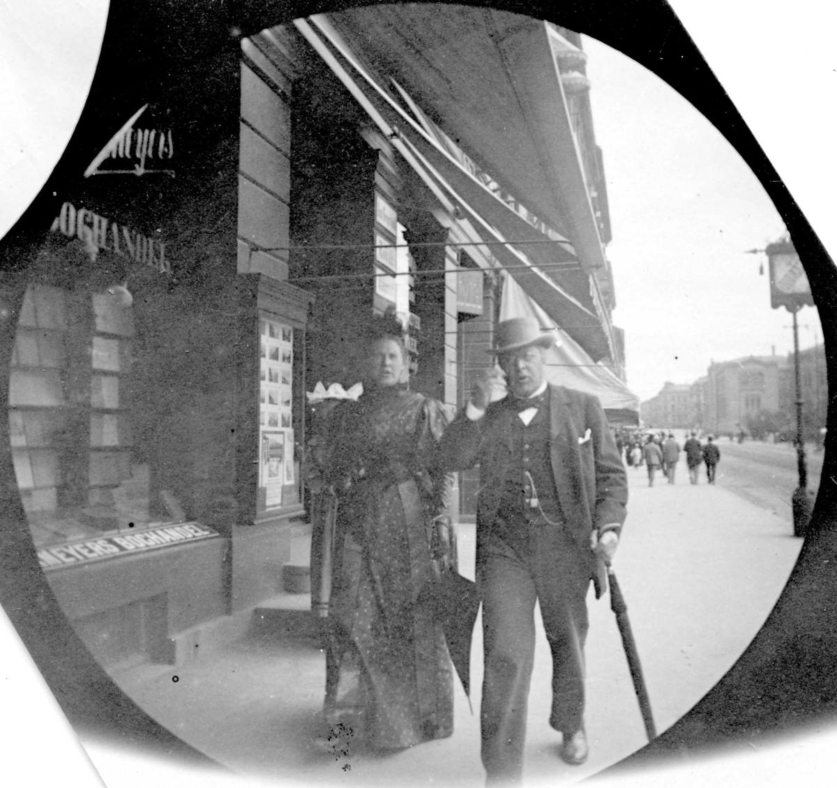 Assessor Reimers og frue spaserer på Karl Johans gate, Oslo, ved bokhandel.