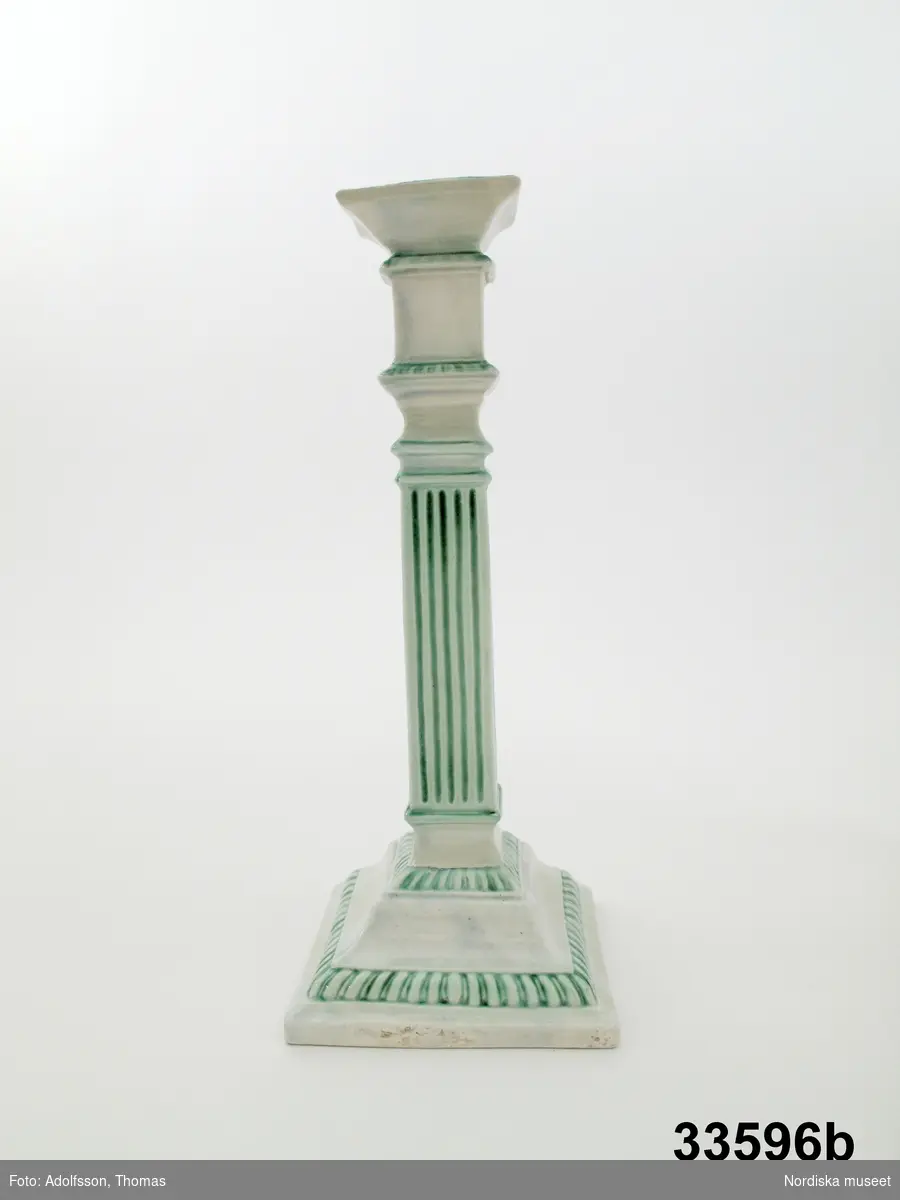 Ljusstake av vitglaserat flintgods i form av refflad pilaster på fyrkantig fot med grön dekor. Omärkt, tillverkad omkring 1800.
/Annika Tegnér 2008