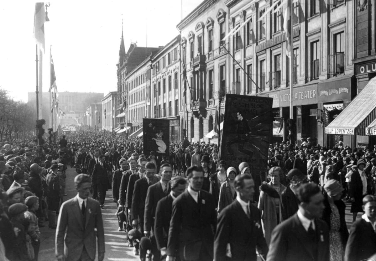 1. mai-tog, Karl Johans gate. 1930. Menn og kvinner. Faner. Flagg. Slottet i bakgrunnen.