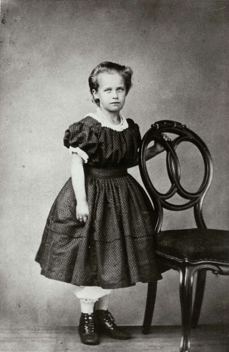 Portrett, Sofie Dahl, senere gift Gran, sorenskriver Dahls datter. Pike i kjole poserer ved stol i atelier. Hun er født ca. 1850.