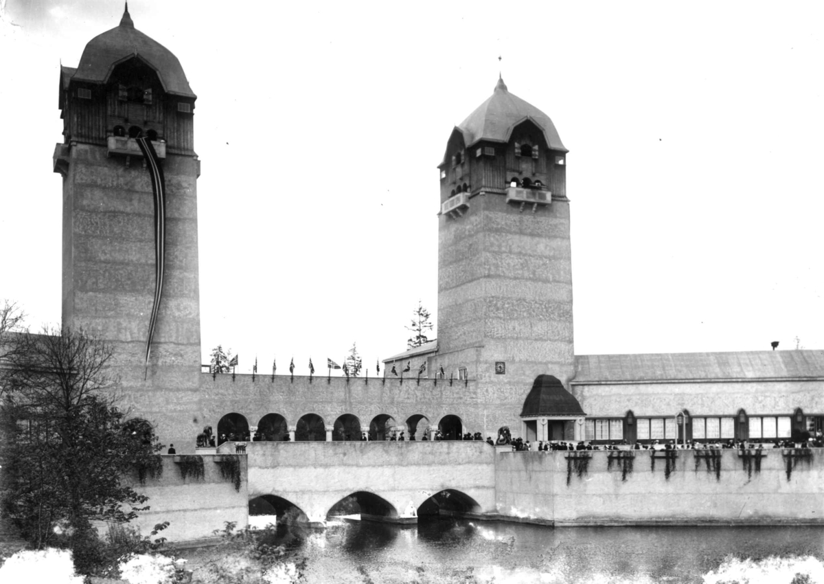 Jubileumsutstillingen på Frogner, Oslo, 1914. Festbygning og industribygning. Publikum spaserer
på broene. Dam i forgrunnen.