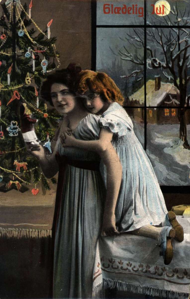 Julekort. Jule og nyttårshilsen. Mor og datter står ved et juletreet. Utsikt til vintermotiv. Datert 23.12.1910.