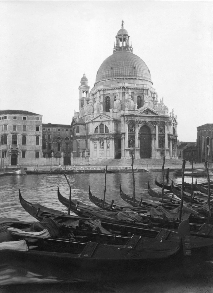Flere gondoler forankret på kanalen i Venezia. Mariakirken i bakgrunnen. Robsahm og Lund.