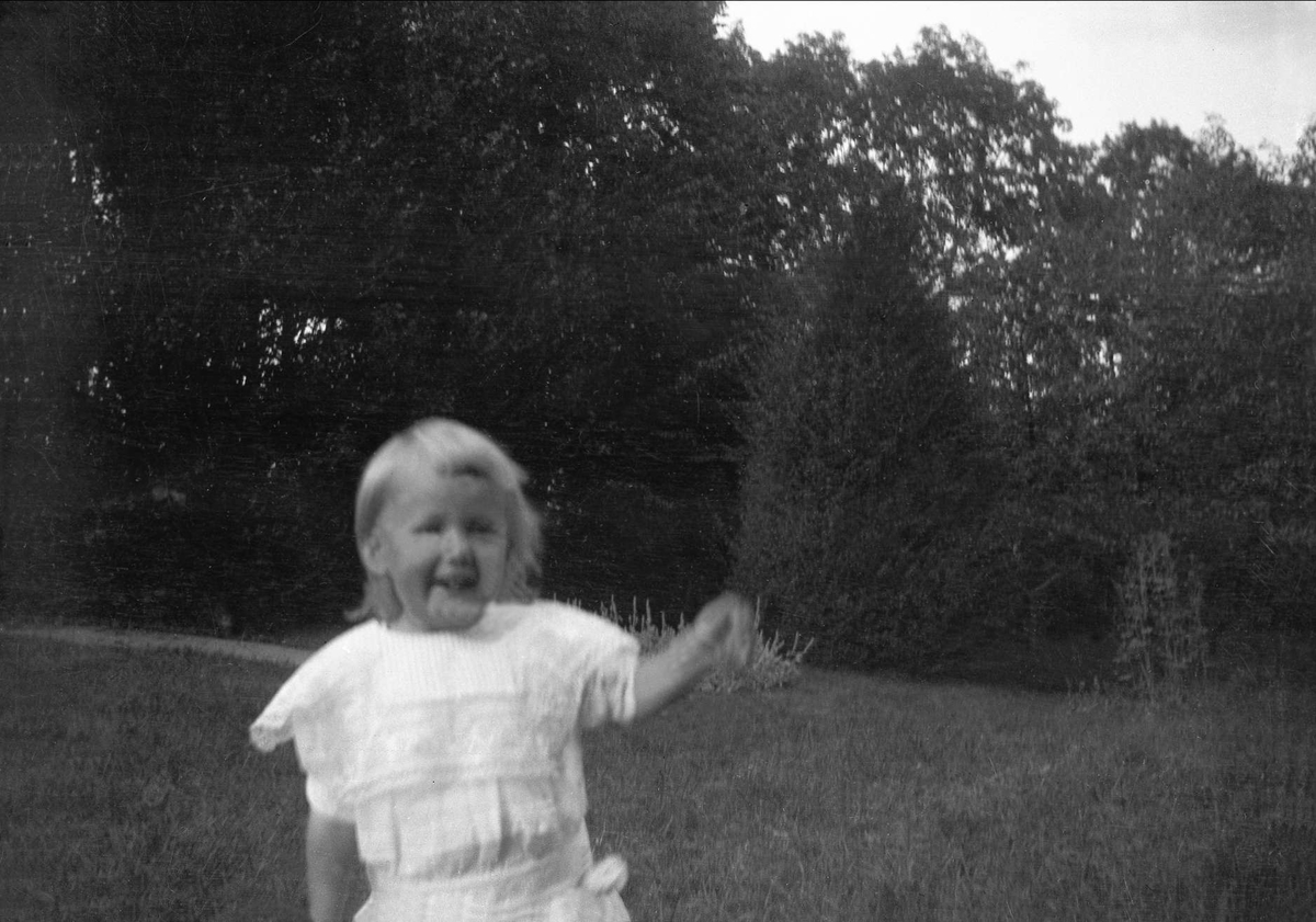 Et barn springer i en hage. Robsahm og Lund.