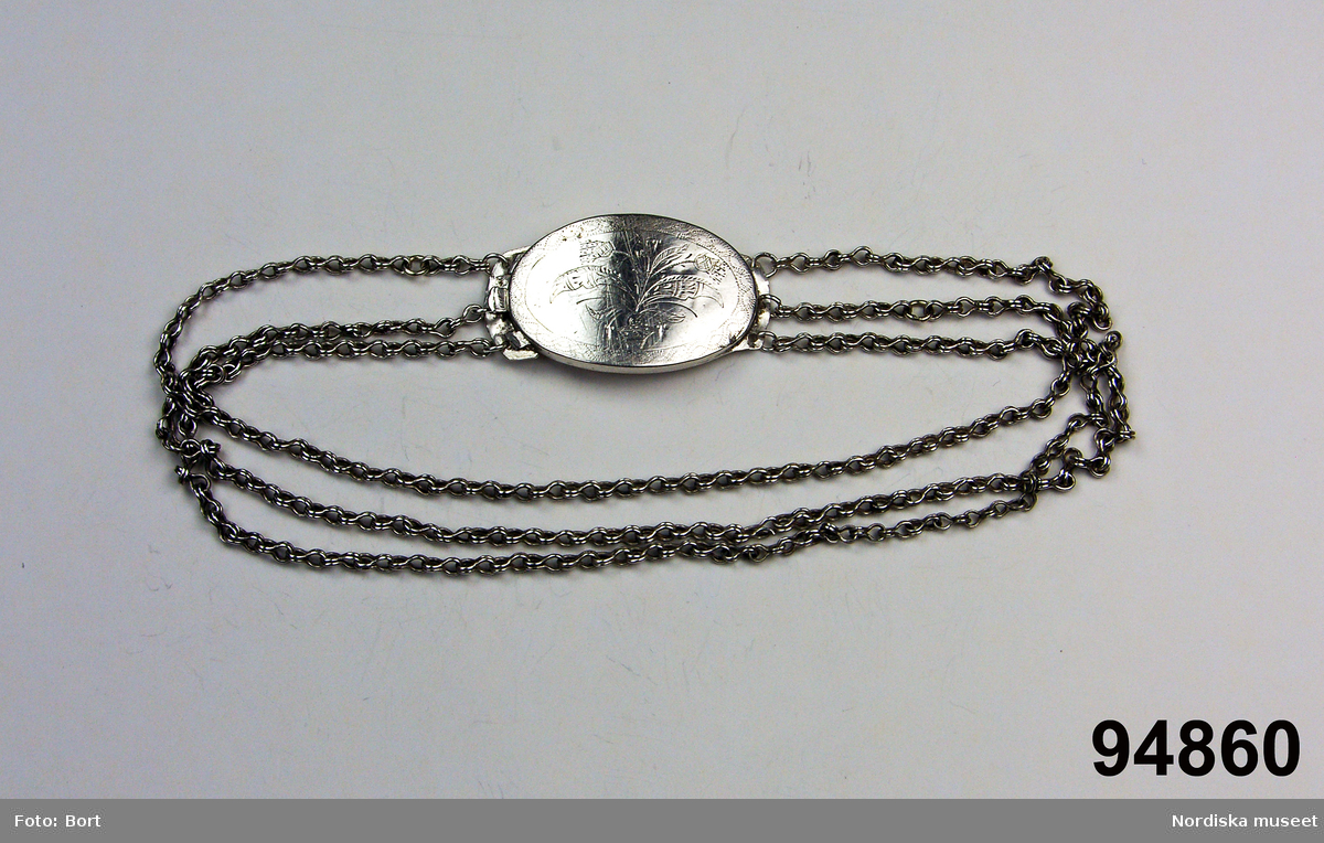 Ovalt lås av silverplåt , med graverad och trembolerad  blomdekor. Tre Tre halskedjor. Stämpat POS. Okänd silversmed
/Berit Eldvik 2006-12-04

