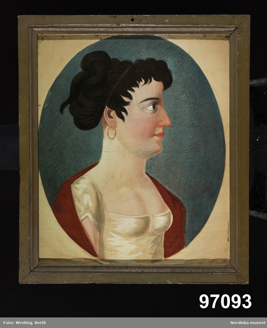Porträtt, kvinna i profil, bröstbild. Huvudet stort i förhållande till kroppen.