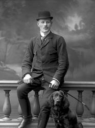 Gruppeportrett, mann i rideklær og en fuglehund.