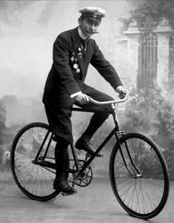 Portrett, mann med uniformslue, medaljer og sykkel.