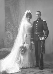 Gruppeportrett, bryllupsbilde. Han i uniform, hun i hvit bru