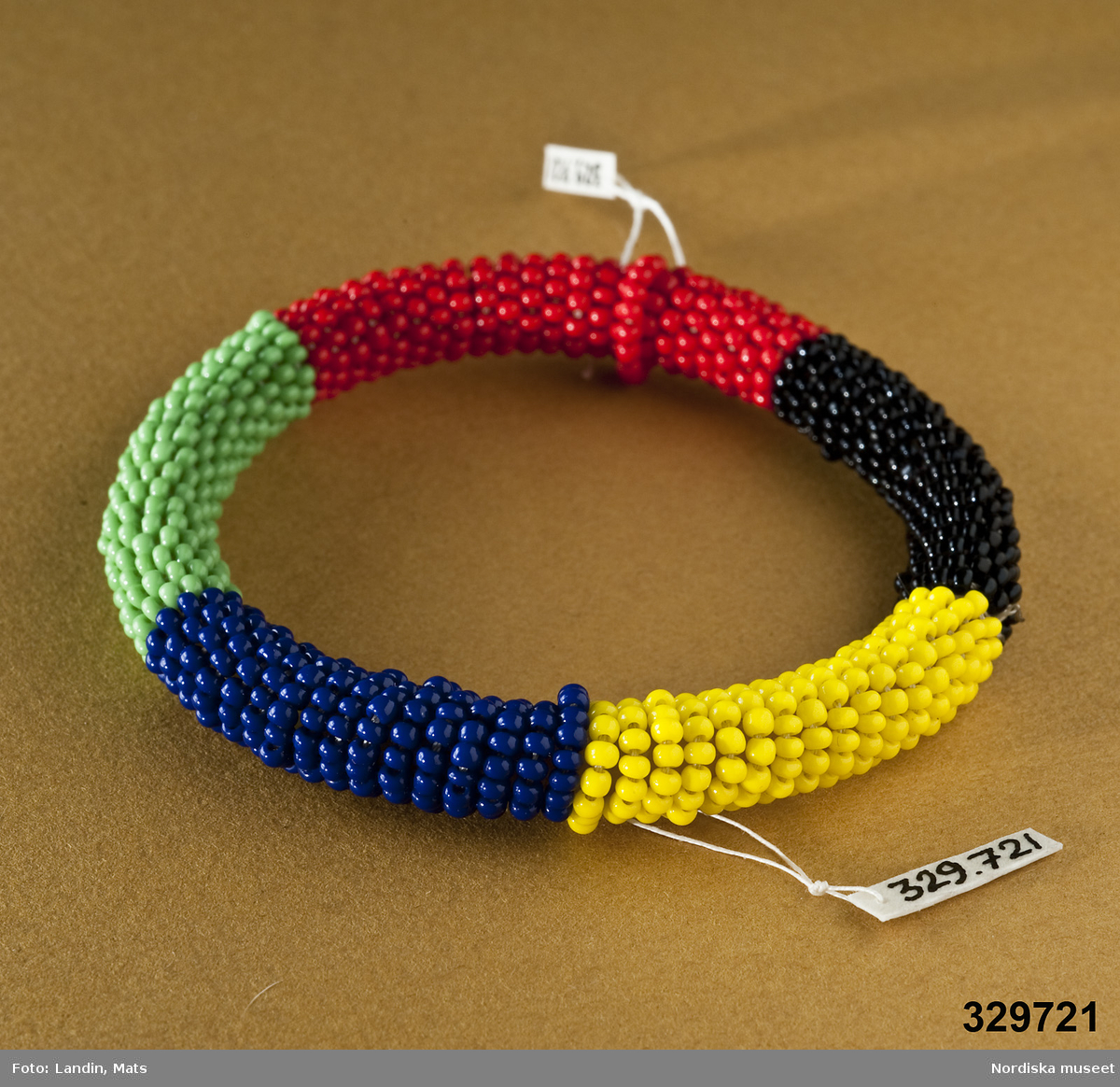 Runt armband prytt med små plastpärlor i gult, lila, svart, grönt och rött. Afrikanska influenser.
/Zingoalla Rosenqvist 2009-02-05
