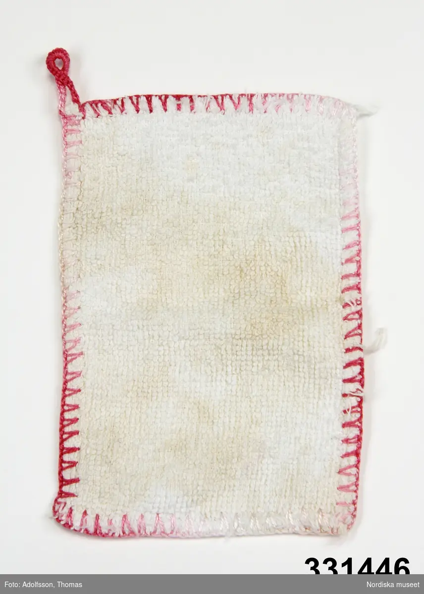 Tvättlapp av vit frotté för dockor. Med hängare av bomullsgarn och kantstickning i olika nyanser av rosa. 
/Karin Dern 2011-09-13