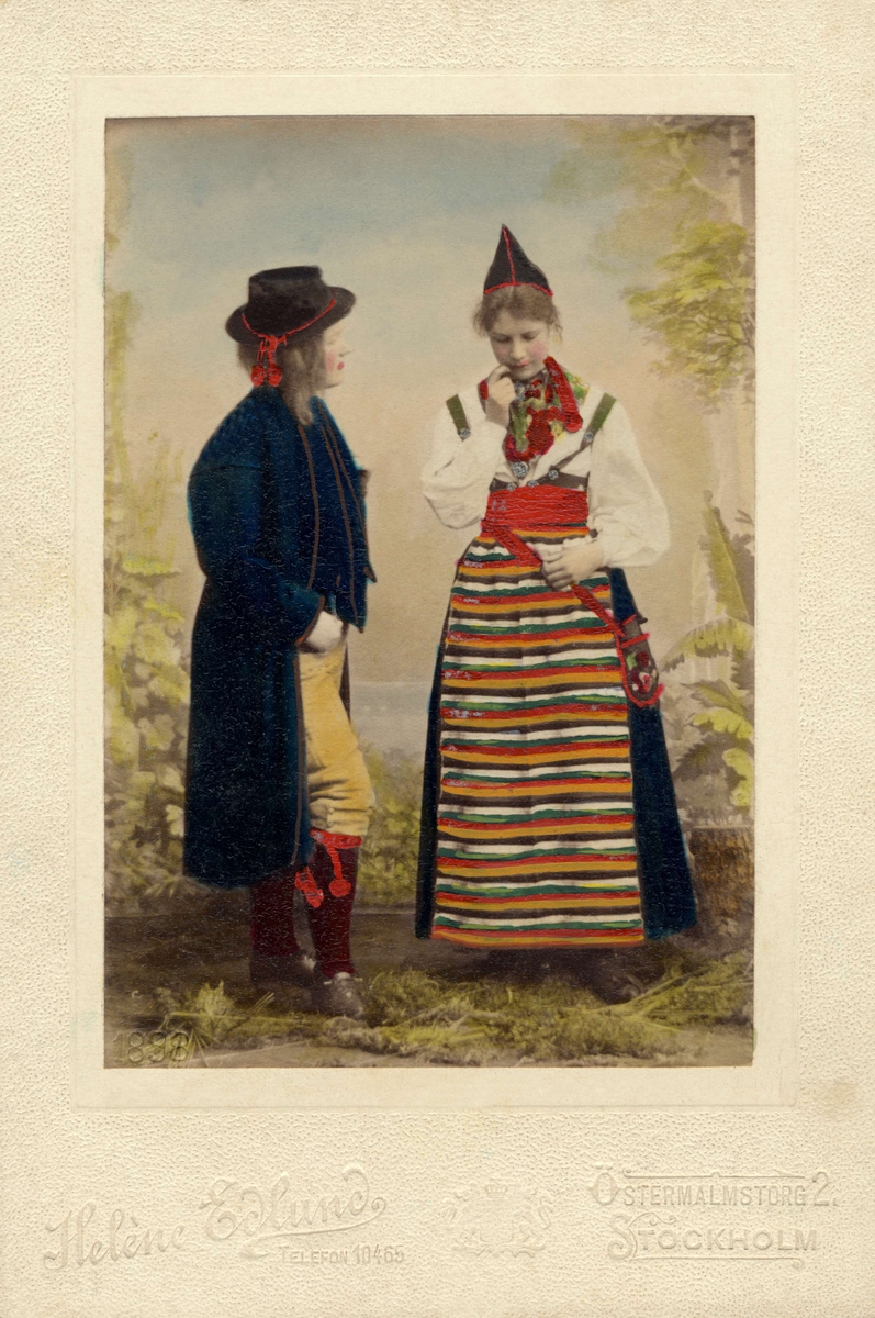 En kvinna och man poserar i folkdräkt. handkolorerat fotografi.