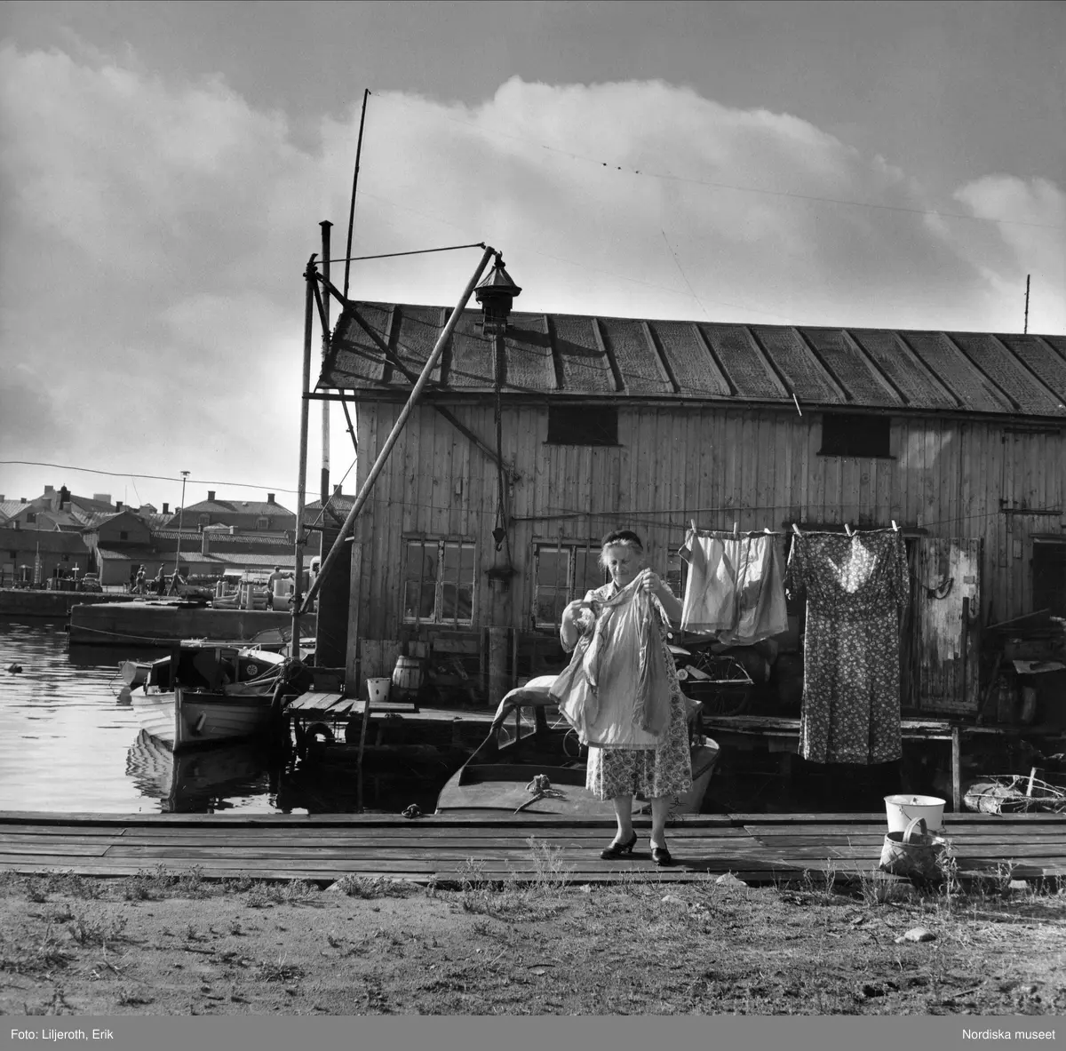 Kvinna h&auml;nger upp tv&auml;tt i invid en av fastigheterna vid Hamngatan vid Gamlebyviken i V&auml;stervik. 