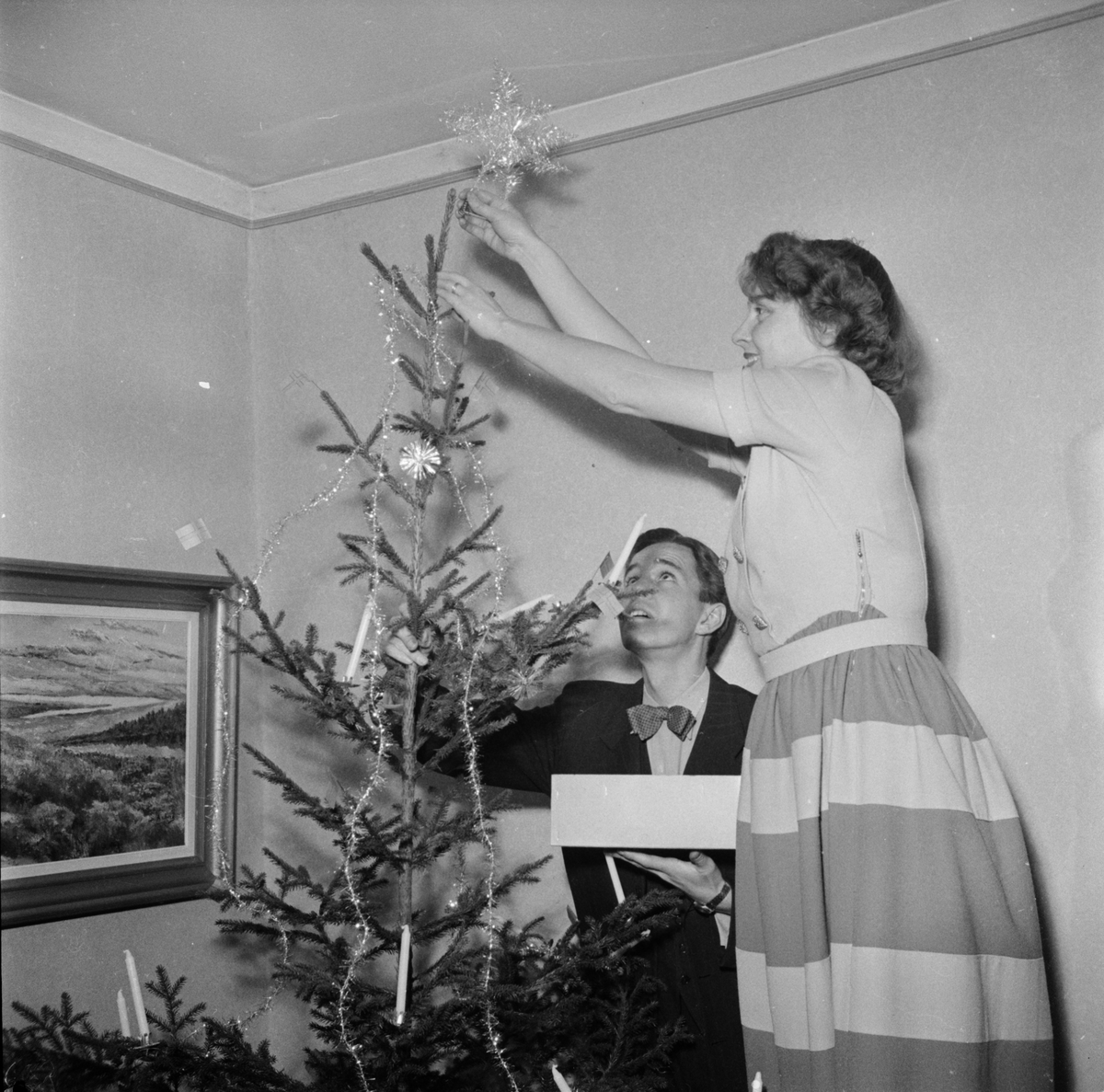 Julafton kvinna sätter stjärna i julgran, Uppsala 1949