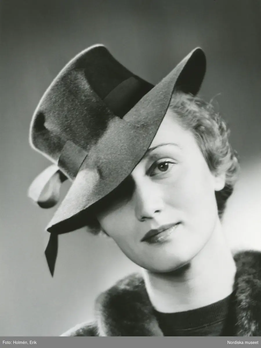 Porträtt av kvinna i hatt med band och tunn pälsboa runt halsen ...