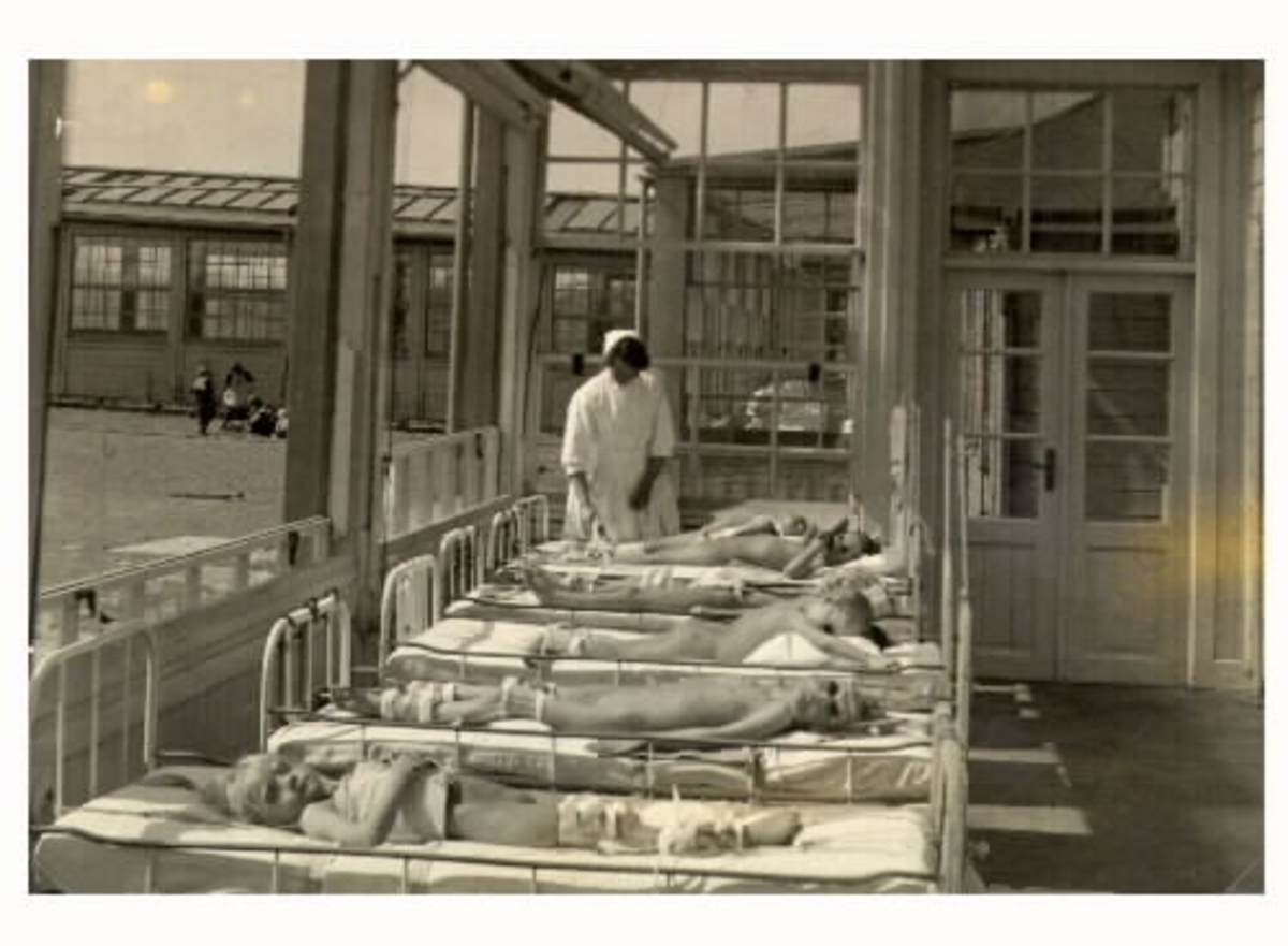 Interiör från småflickornas solveranda på Kustsanatoriet Apelviken. En sköterska ser till patienterna som får sol i sina sjuksängar.