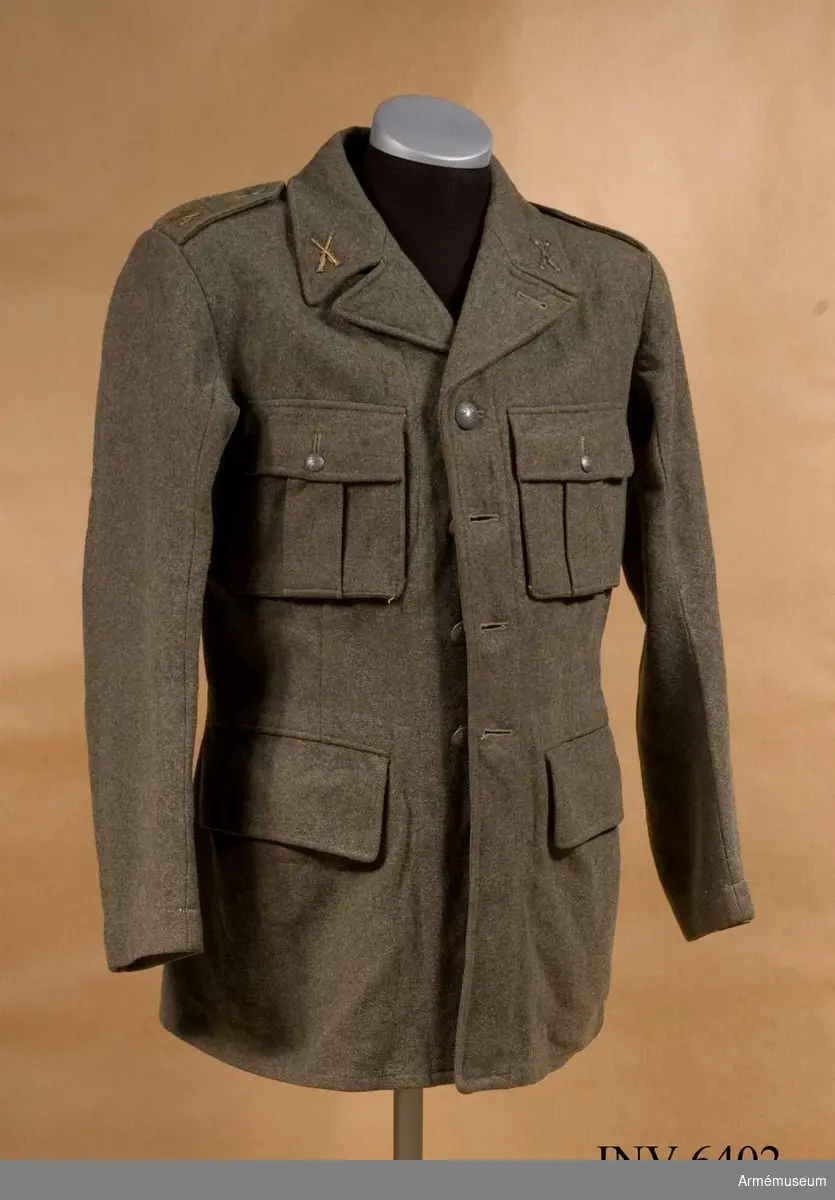 Stl 96. Av samma snitt som uniform m/1939. Daglig dräkt av gråbrungrönt tyg. Bäres till gråbrungröna byxor. Tjänstetecken mattförgyllda.