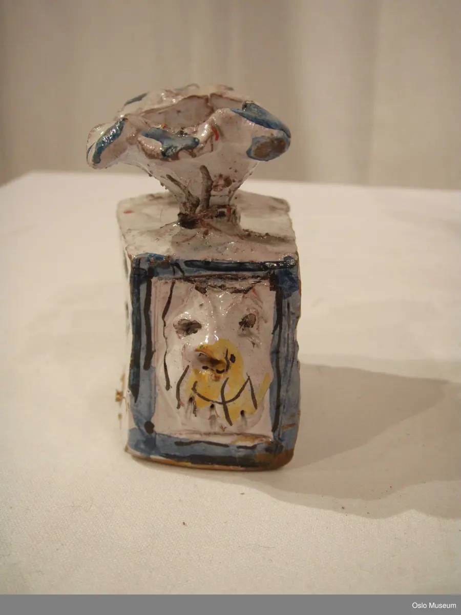 Scenografimodell av keramikk. Glasert i hvit bunnfarge med dekor/detaljer i blått og gult. 7 deler. Spesiallaget oppbevaringseske.