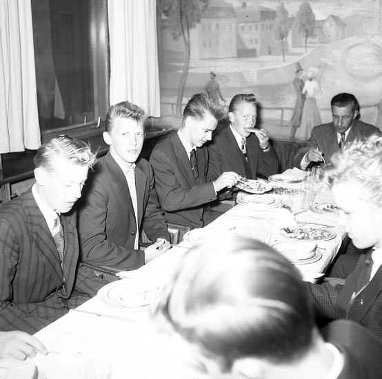 "Bohusläningen bjuder på middag på Havet 9 oktober 1955".
Bakom männen i restaurang Havet syns en väggmålning av konstnären Pelle (Per Axel) Åberg (1909 - 1964), Stockholm.